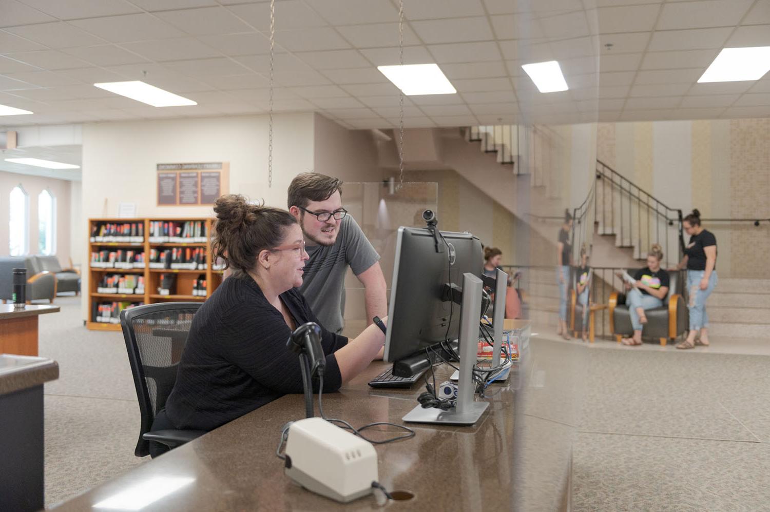 一名工作人员和一名学生正在查看国王图书馆的数据库